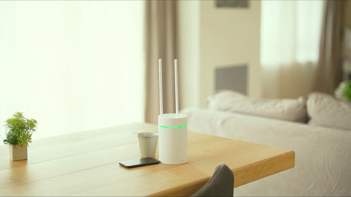 밝은 식탁 위의 와이파이 공유기와 휴대폰, 컵