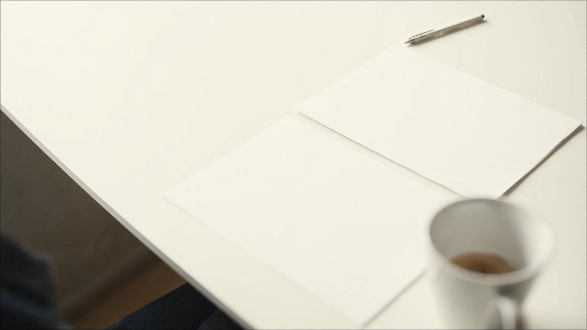 밝은 책상 위 겹쳐 둔 서류와 펜, 흰 컵