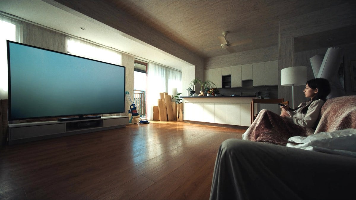 소파에서 리모컨을 들고 TV를 보는 여성