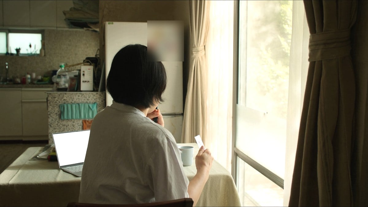 식탁에서 카드를 들고 노트북을 보는 여성