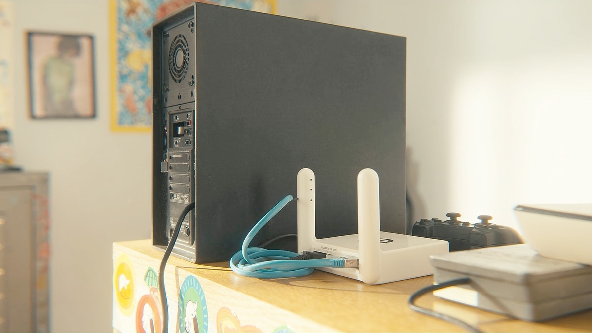 햇살 드는 방 책상 위 게임용 컴퓨터 본체와 랜선으로 연결된 공유기
