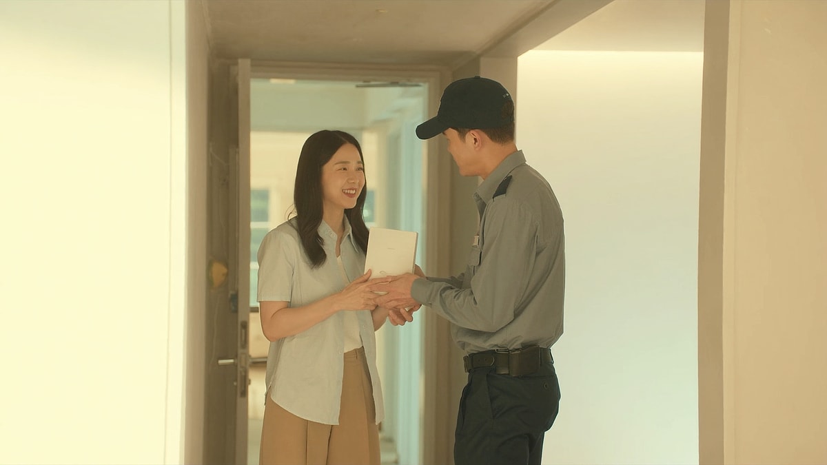 아파트 현관에서 설치 기사님에게 상자를 건네받으며 웃는 여성