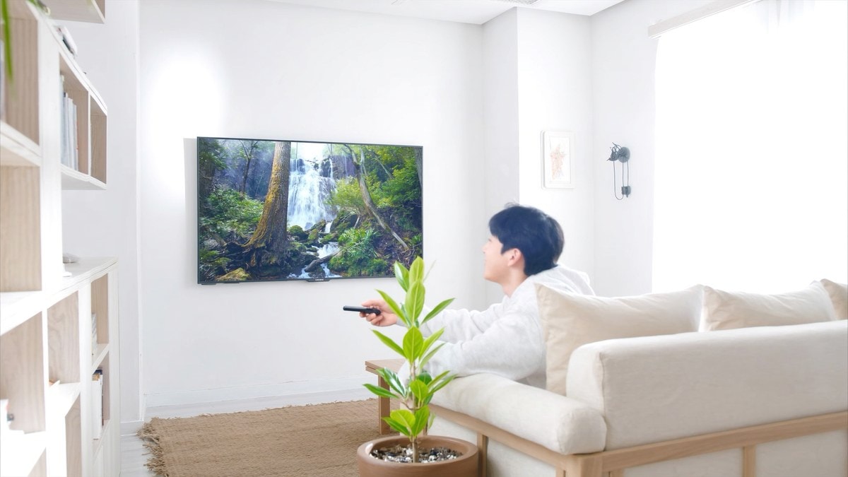거실 소파에서 리모컨으로 폭포 풍경 TV를 보는 남성